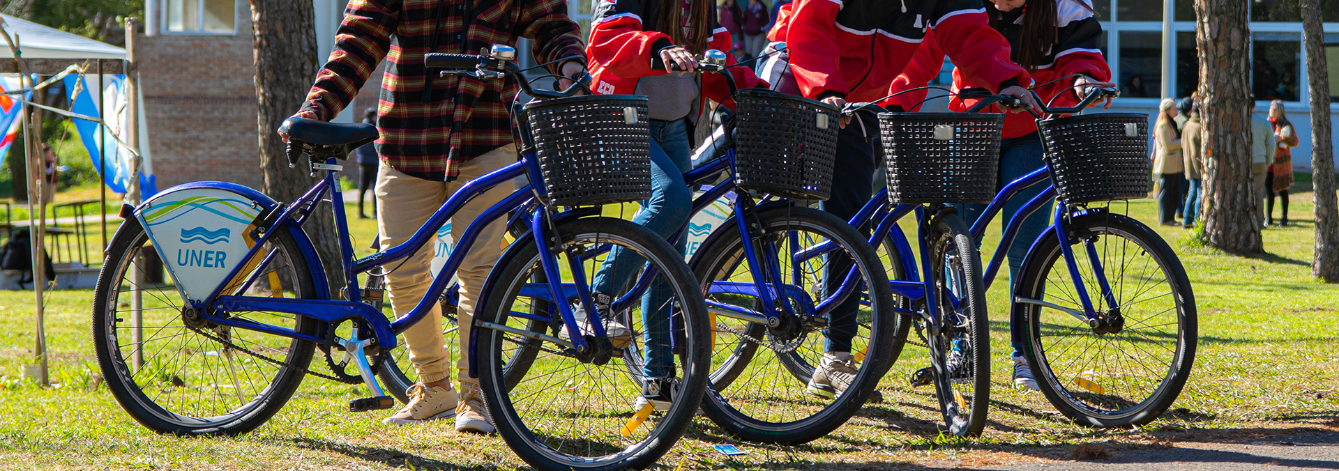 Estudiantes con bicicletas que tienen el logo de la UNER