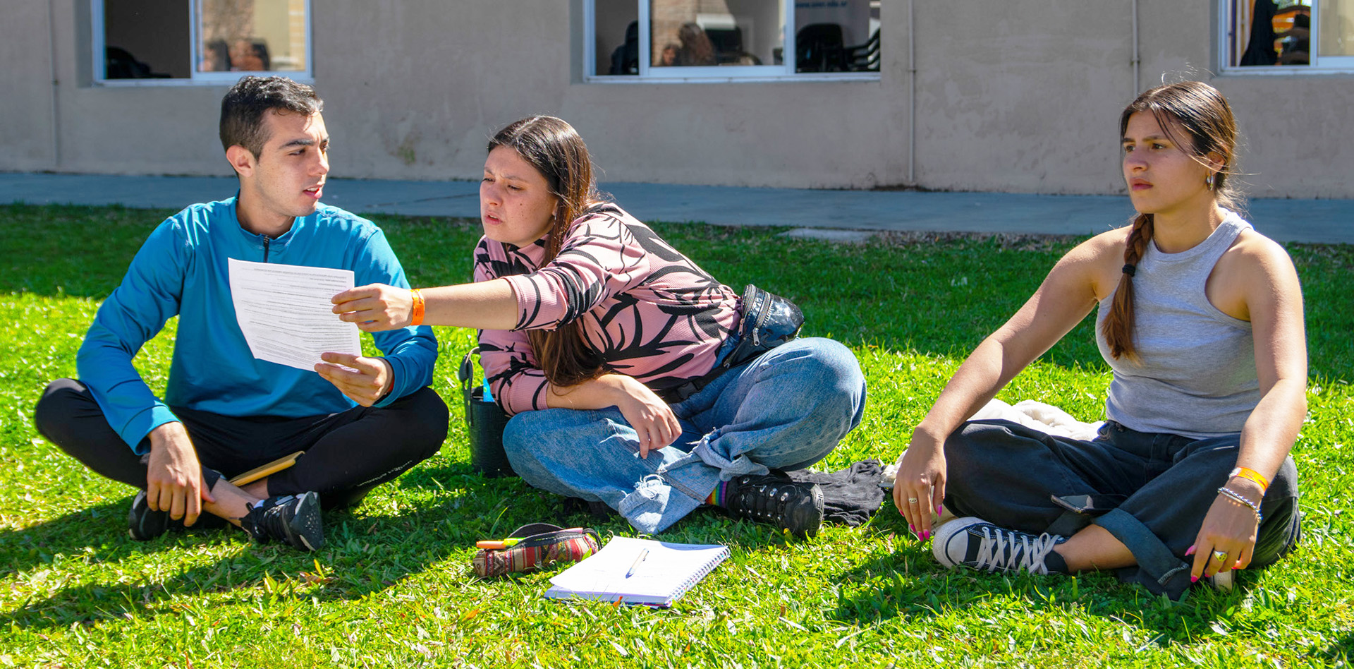 Foto de estudiantes sentados en el patio de una facultad